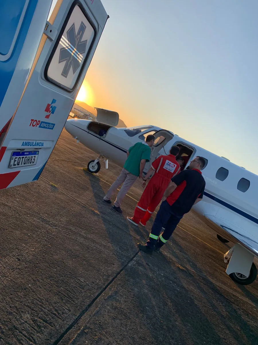 Equipe recebendo paciente de avião ao pôr do sol
