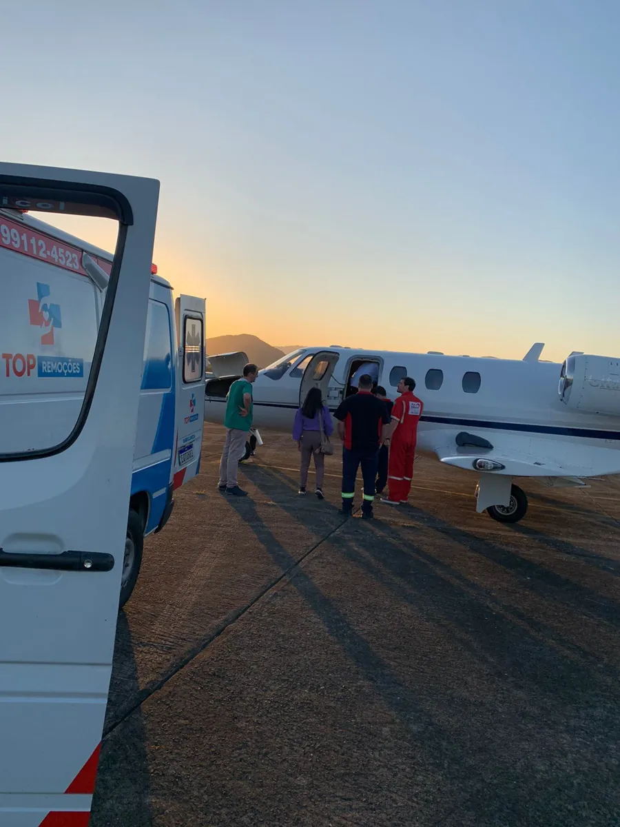 Ambulância de portas abertas próxima a avião